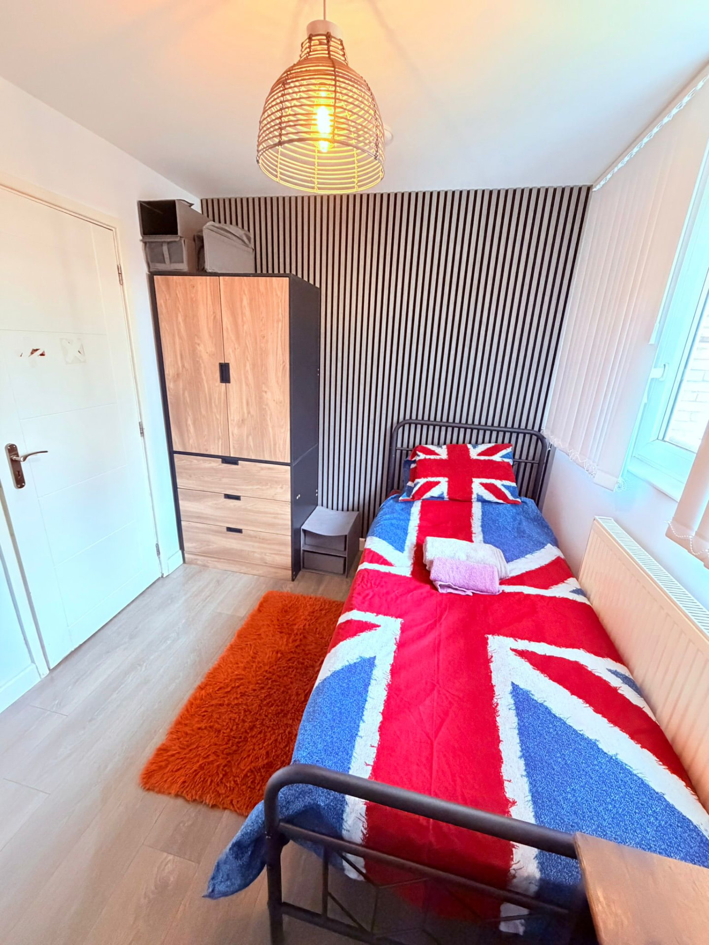 Single room with Union Jack bedding, wardrobe and slatted feature wall